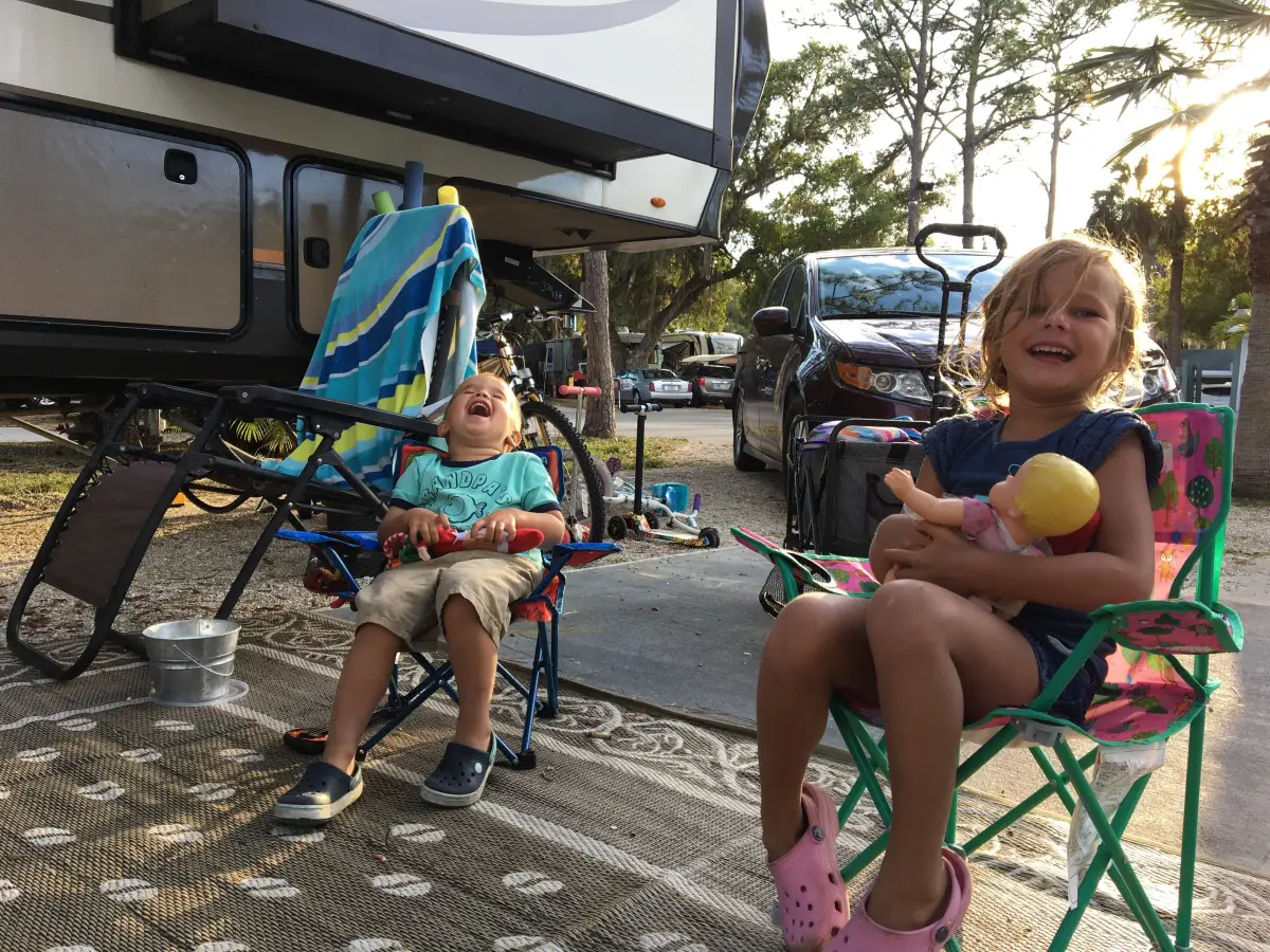 Duke and Amelia laughing in camp chairs beside the fifth wheel