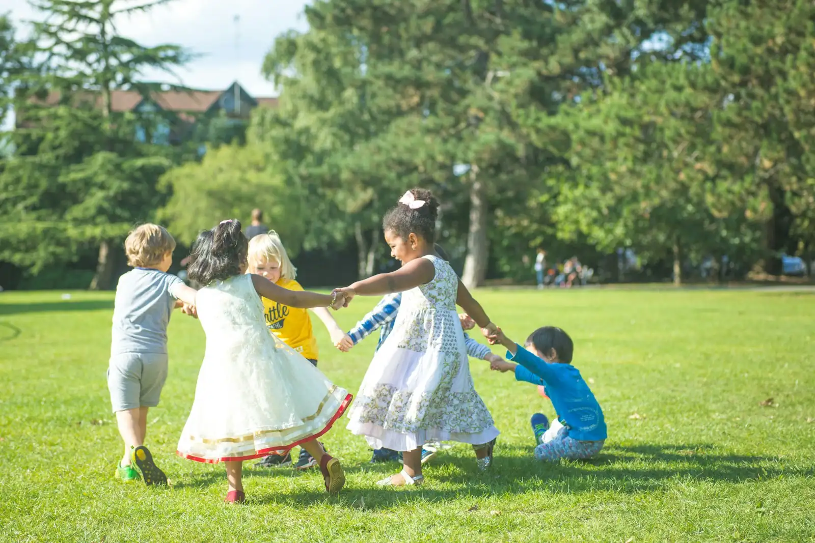 Children holding hands in a circle on a lawn