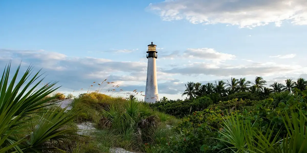Scenic view of Cape Florida Lighthouse surrounded by lush greenery under a blue sky.