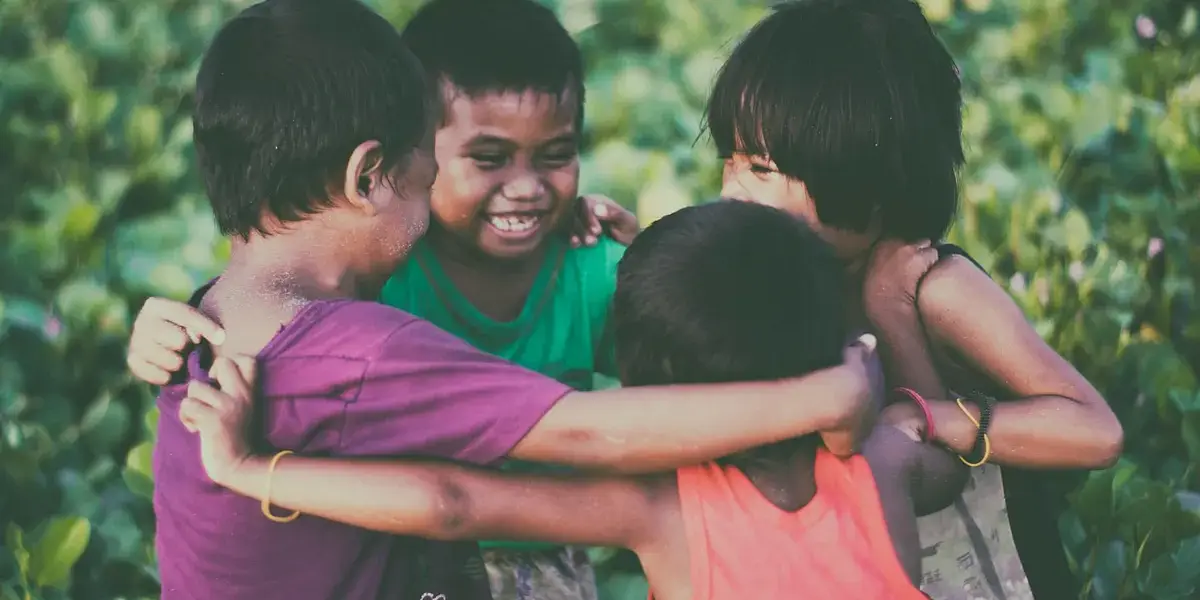 Group of children hugging and playing joyfully in Donsol, Bicol, Philippines outdoors.