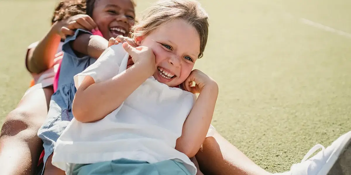 Joyful children smiling and playing on a sunny day outdoors.