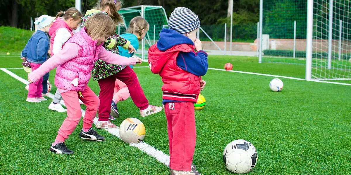 Kids having fun playing soccer outdoors on a sunny day in a park.